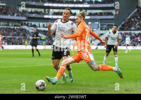 Derby, Derbyshire, Großbritannien. März 2024. Hayden Coulson aus Blackpool überquert den Ball unter Druck von Kane Wilson aus Derby County während des Spiels der Sky Bet League 1 zwischen Derby County und Blackpool im Pride Park, Derby am Freitag, den 29. März 2024. (Foto: Jon Hobley | MI News) Credit: MI News & Sport /Alamy Live News Stockfoto