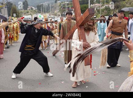 CUENCA-VIACRUSIS-SEMANA SANTA-TURI Cuenca, Ecuador 29 de marzo de 2024. Descalzo y con una cruz de madera de MAS de 200 libras sobre sus hombros, Marco Pintado recorrio las 14 estaciones del Via crucis de la parroquia Turi en Cuenca. El personifica a a Jesus desde hace anos, cuando heredo el legado de su padre, que Practice este rito por 14 anos, en la procesion en Honor al Senor de la Buena Muerte, una de las Mas tradicionales que se celebran en la Capital azuaya en Semana Santa. La procesion, que inicio a las 09:30 de hoy, viernes 29 de marzo de 2024, en los Tres Puentes, es liderada por un gru Stockfoto