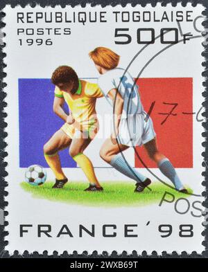 Von Togo gedruckte Briefmarke mit annullierter Briefmarke, die die französische Flagge, die Actionszene, die Fußball-Weltmeisterschaft 1998, Frankreich, um 1996, zeigt. Stockfoto