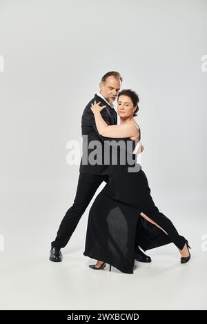Seitenansicht eines attraktiven Paares in einer Tangotanz-Pose auf grauem Hintergrund Stockfoto