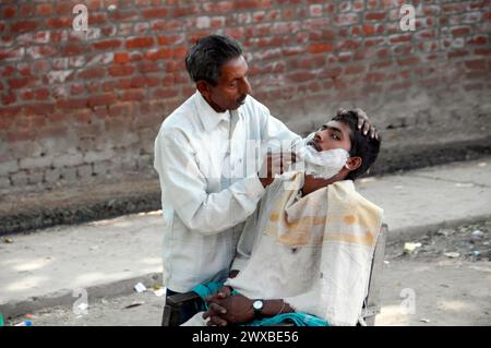 Ein Friseur rasiert einen Kunden draußen auf der Straße, Jaipur, Rajasthan, Nordindien, Indien Stockfoto