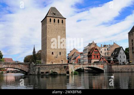 Turm der ehemaligen Stadtbefestigung, Bootsfahrt auf der L'ILL, Straßburg, Elsass, historischer Turm und Brücke auf einem Fluss mit klarem Himmel Stockfoto