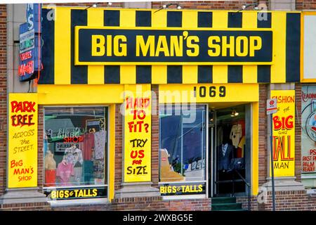 Fassade eines großen Ladens mit auffälligem gelbem und schwarzem Neonschild, Big man's Shop, Einzelhandel, Spezialbekleidungsgeschäft, Männer, Übergewicht, Adipositas Stockfoto