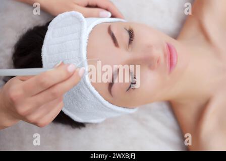 Der Kosmetiker macht das Verfahren der Gesichtsreinigung einer schönen, jungen Frau in einem Schönheitssalon. Kosmetik und professionelle Hautpflege. Stockfoto