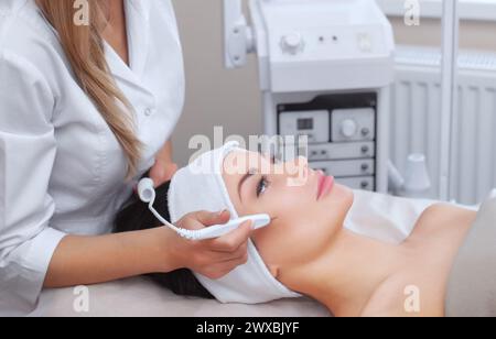 Die Kosmetikerin macht die Prozedur Behandlung von Couperose der Gesichtshaut einer schönen, jungen Frau in einem Schönheitssalon. Kosmetologie und Professi Stockfoto