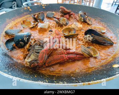 Reis mit Meeresfrüchten im Stil von Nordspanien. Muscheln, Fisch, Krabben, Muscheln und cremiger Reis in einer großen Eisenpfanne. Mittagessen am Meer. Stockfoto