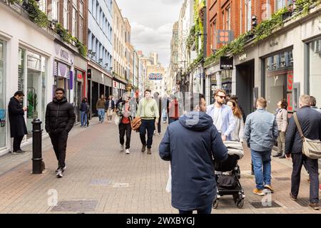 Shopper und Touristen in der Carnaby Street, dem legendären Zentrum, das Mode, Kultur und pulsierendes Straßenleben im Herzen von Soho, London, verbindet. Stockfoto