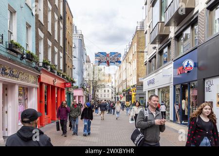 Menschenmassen, Touristen und Shopper machen einen Spaziergang entlang der Londoner Carnaby Street, bekannt für ihre Modeboutiquen, einzigartige Geschäfte und lebhafte Atmosphäre. Stockfoto