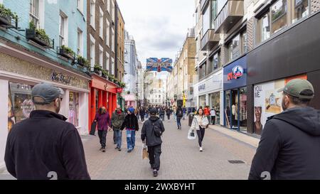 Menschenmassen, Touristen und Shopper machen einen Spaziergang entlang der Londoner Carnaby Street, bekannt für ihre Modeboutiquen, einzigartige Geschäfte und lebhafte Atmosphäre. Stockfoto