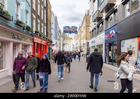 Menschenmassen, Touristen und Shopper machen einen Spaziergang entlang der Londoner Carnaby Street, bekannt für ihre Modeboutiquen, einzigartige Geschäfte und lebhafte Atmosphäre. Stockfoto