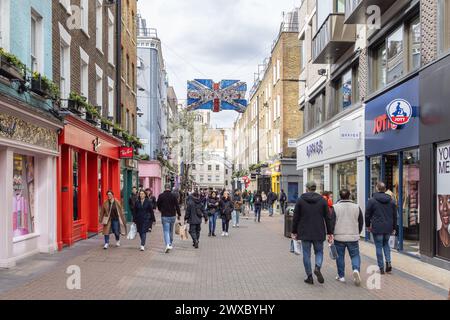 Menschenmassen, Touristen und Shopper machen einen Spaziergang entlang der Londoner Carnaby Street, bekannt für ihre Modeboutiquen, einzigartige Geschäfte und lebhafte Atmosphäre. Stockfoto