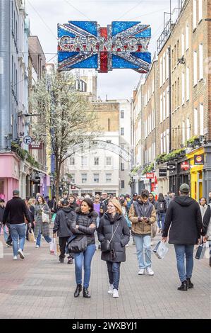 Menschenmassen, Touristen und Shopper machen einen Spaziergang entlang der Londoner Carnaby Street, bekannt für ihre Modeboutiquen, einzigartige Geschäfte und lebhafte Atmosphäre. Stockfoto