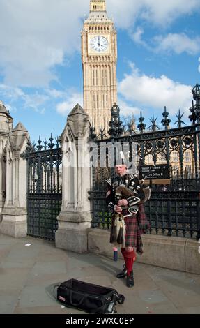 Ein einsamer schottischer Piper vor dem Parlament, London, Großbritannien; Big Ben im Hintergrund, schottische Tracht; Kilt; Dudelsack Stockfoto