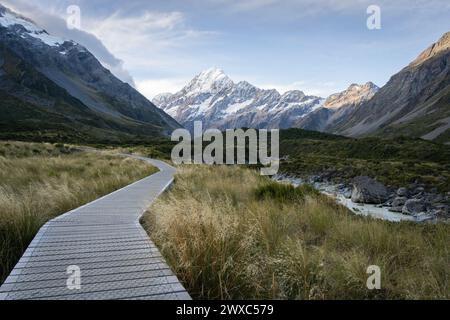 Hölzerne Promenade führt durch das wunderschöne Alpental mit verschneiten Bergen im Hintergrund, Neuseeland. Stockfoto