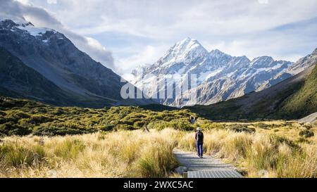 Touristen wandern den Weg durch das wunderschöne Alpental mit riesigen, schneebedeckten Bergen, Mt Cook, Neuseeland. Stockfoto