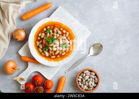 Traditionelles türkisches Essen Kidneybohnen mit Olivenöl, Zwiebeln und Tomatenpaste in einer Keramikplatte auf rustikalem Hintergrund Stockfoto