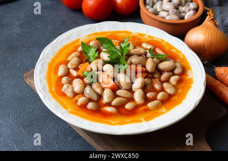 Traditionelles türkisches Essen Kidneybohnen mit Olivenöl, Zwiebeln und Tomatenpaste in einer Keramikplatte auf rustikalem Hintergrund Stockfoto