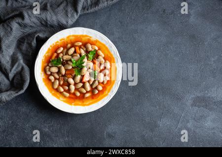 Traditionelles türkisches Essen Kidneybohnen mit Olivenöl, Zwiebeln und Tomatenpaste in einer Keramikplatte auf rustikalem Hintergrund Stockfoto