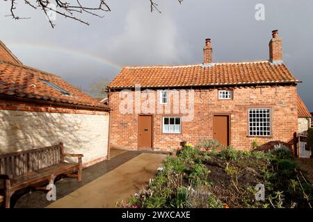 Hinter dem Cottage, in dem einst Mrs. Smith in Navenby, Lincolnshire, lebte, erscheint ein Regenbogen. Das von der örtlichen Gemeinde gerettete, bescheidene Haus von Mrs. Smith wurde 1999 erstmals als Museum eröffnet. Durch die Zusammenarbeit von lokalen Freiwilligen und dem District Council zieht die Stätte Besucher und Lob von weit und breit an. Stockfoto