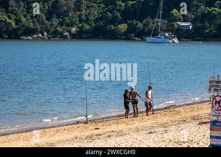 Männer mit zwei Angelruten fischen am Strand, Palm Beach, Sydney, Australien, 2024 Stockfoto