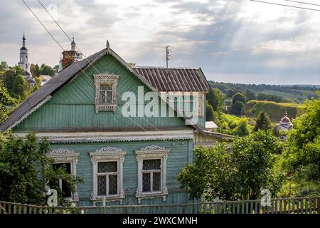 Ländliches Holzhaus mit geschnitzten Rahmen im Hintergrund der Kirchen in Maloyaroslavets (Malojaroslavec, Maloyaroslavec), Russland - Juni 2019 Stockfoto