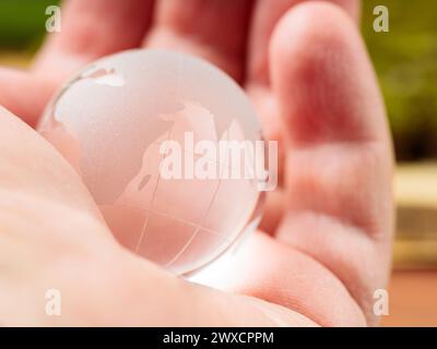 Transparente Glaskugel in der Handfläche des Menschen, Konzept des Erdtags und Umweltschutz Stockfoto