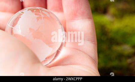 Transparente Glaskugel in der Handfläche des Menschen, Konzept des Erdtags und Umweltschutz Stockfoto