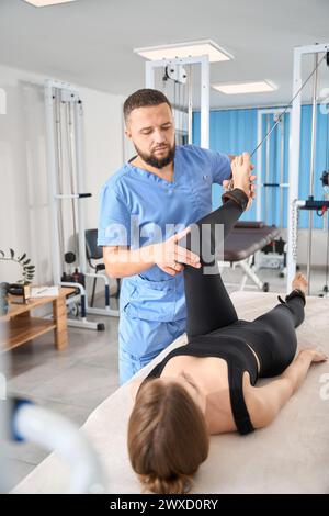 Der Physiotherapeut verwendet ein spezielles Trainingsgerät, um mit dem Patienten zu arbeiten Stockfoto