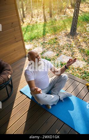 Ein älterer Mann sitzt in einer Yoga-Pose Stockfoto