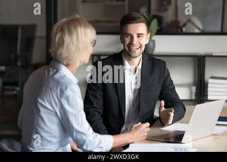 Glücklicher junger Geschäftsexperte, der mit einem Senior-Kunden spricht Stockfoto