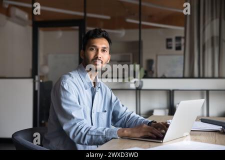 Selbstbewusster, gutaussehender junger indischer Unternehmer, der am Computer arbeitet Stockfoto