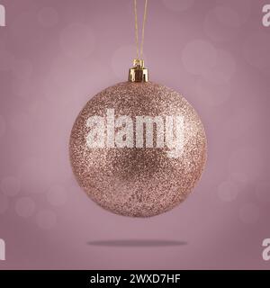 Wunderschöne glitzernde Weihnachtskugel, die auf farbigem Hintergrund hängt Stockfoto