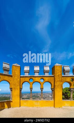 Maurische Bögen des bogenförmigen Innenhof mit den gelb bemalten Wänden des Pena Palace, mit der Sintra Gebirgskette und dem Atlantischen Ozean auf der Stockfoto