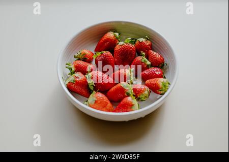 Die frischen roten Erdbeeren in einer Schüssel auf einem weißen Tisch Stockfoto
