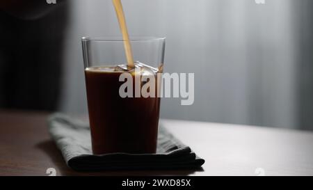 Mann, der Eiskaffee mit Espresso im Glas auf Holztisch macht, großes Foto Stockfoto