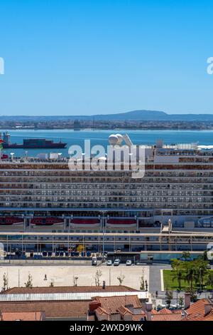 Blick auf ein großes Kreuzfahrtschiff, das im Hafen von Lissabon am Tejo angedockt ist, mit einem Containerschiff im Hintergrund. Stockfoto