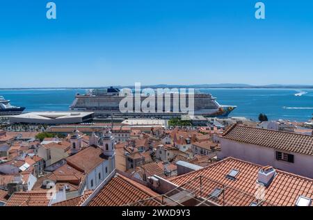 Blick von Lissabons Stadtteil Alfama auf ein großes Kreuzfahrtschiff, das im Hafen angedockt ist, mit Vergnügungsbooten und Yachten, die herumsegeln. Stockfoto