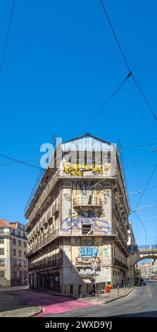 Fassade voller Straßenkunst und Graffiti auf einer Straße in Portugal mit Straßenbahnschienen und Kabeln. Stockfoto