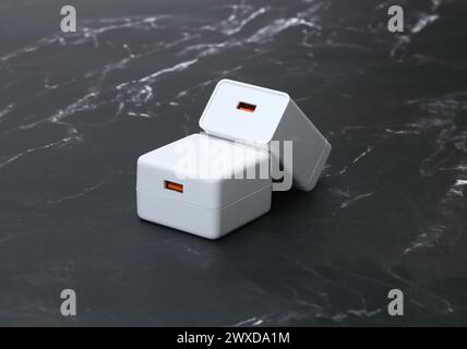 Weiße Smartphone-Ladegeräte auf schwarzem Marmorhintergrund Stockfoto