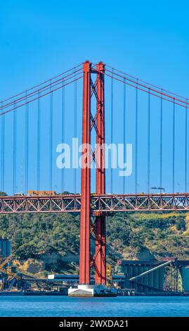 Am 25. April wurde die Brücke aus rotem Stahl wie das Goldene Tor über den Tejo in Lissabon gebaut, mit Auto- und Lastwagenverkehr an einem sonnigen Tag mit klarem blauem Himmel Stockfoto