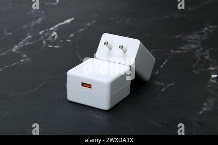 Weiße Smartphone-Ladegeräte auf schwarzem Marmorhintergrund Stockfoto