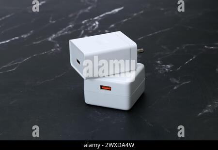 Weiße Smartphone-Ladegeräte auf schwarzem Marmorhintergrund Stockfoto