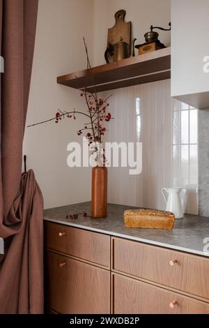 Küchenzeile mit Brotlaib und Blumenvase auf Holzschränken Stockfoto