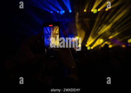 Hände halten das Telefon und machen Fotos auf dem Konzert. Konzerthintergrund Stockfoto