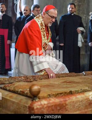 Jerusalem, Israel. 30. März 2024. Der katholische Lichtsamstag in der Grabeskirche. Pierbattista Pizzaballa, Jerusalems Erzbischof tritt in die Kirche ein und hockt sich beim Stein der Sühne. Stockfoto