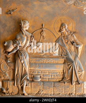 MAILAND, ITALIEN - 8. MÄRZ 2024: Das Metallrelief von Jesus Dialog mit der Samaritanerin am Tor der Kirche Chiesa di Santi Quattro Evangelisti Stockfoto