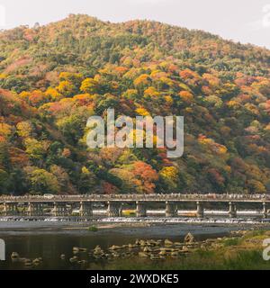 Arashiyama, Kyoto, Herbstlaub auf Hügeln in der Landschaft mit Togetsu-kyo-Brücke. Herbstfarben mit Ahornbäumen. Stockfoto