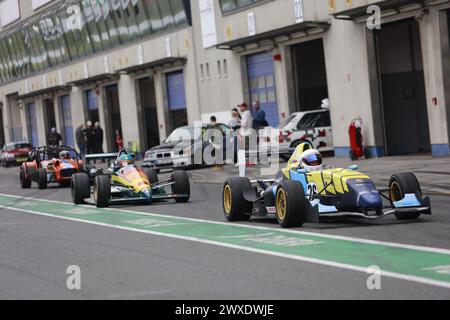 Oschersleben, Deutschland. 30. März 2024. Rennwagen fahren durch die Boxengasse in der Motorsport Arena Oschersleben. Die Motorsport Arena startete mit dem sogenannten Autofrühling in die neue Saison. Den zahlreichen Besuchern wurden kurze Rennen in verschiedenen Rennklassen sowie eine Fahrzeugausstellung und ein Bühnenprogramm angeboten. Die DTM wird Ende April einen Gastauftritt in der Arena geben. Quelle: Matthias Bein/dpa/Alamy Live News Stockfoto