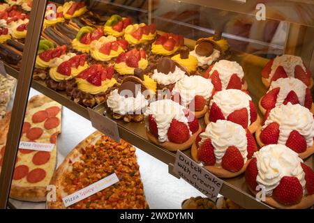 Frische, köstliche süße Kuchen mit Erdbeeren sind im Geschäft hinter einem Glasfenster Stockfoto