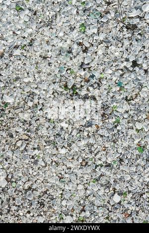 Viele kleine Stücke zerbrochenes zersplittertes Glas in verschiedenen Farben, Draufsicht. Graue, abstrakte, vertikale Tapete. Verlassene Glasfabrik. Stockfoto